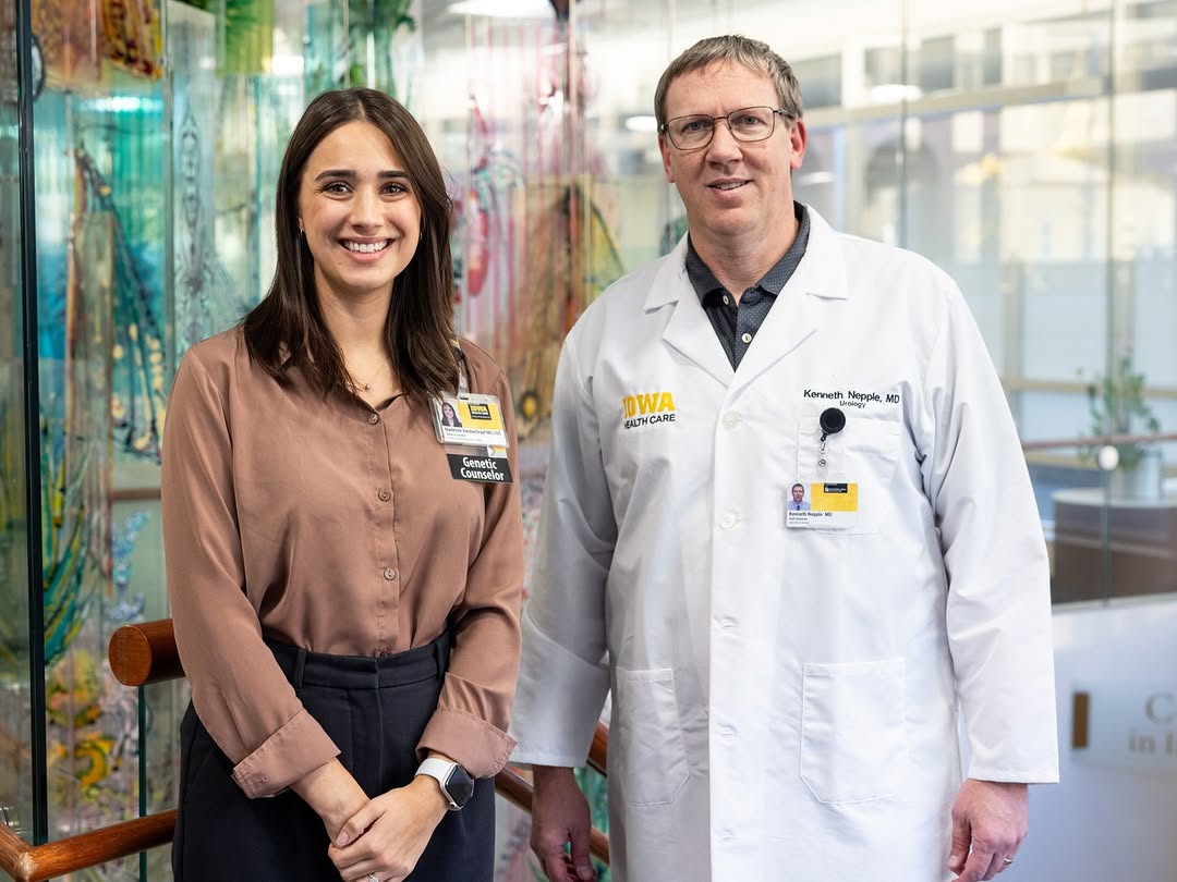 Medium shot of Madeline VanDerGraft, a genetic counselor, and Dr. Kenneth Nepple, a urologist, standing side by side and smiling. VanDerGraft has long dark brown hair and is wearing a dusty-rose butto