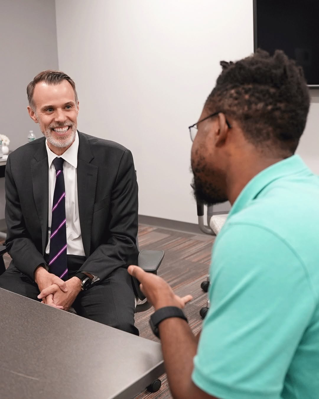 Chancellor David McManus smiling, speaking with medical student Daniel Mbusa