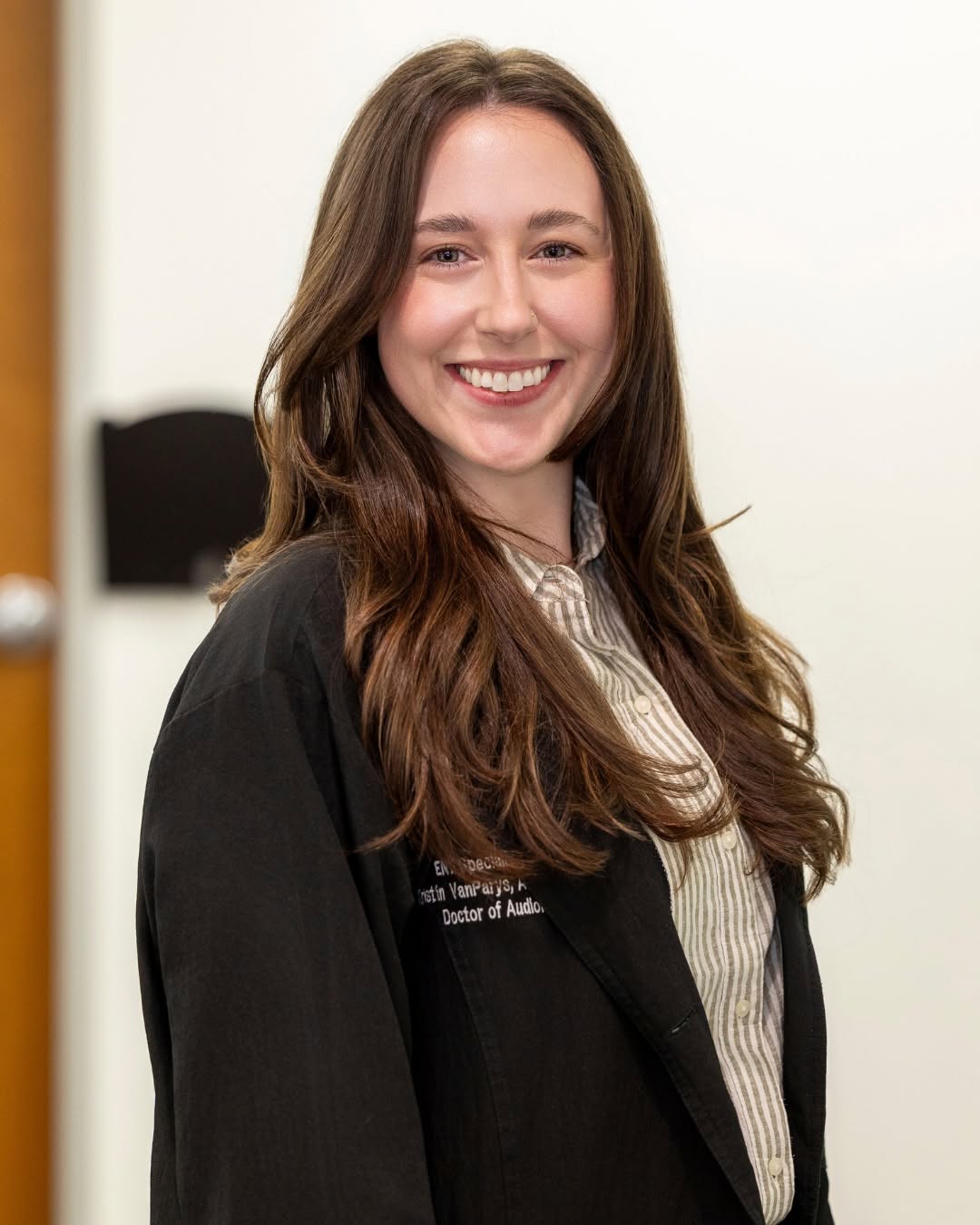 woman with long brown hair in professional health office posing for a headshot photo